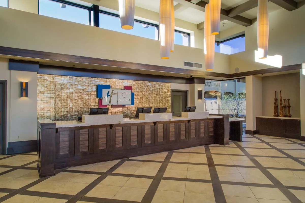 A stylish and modern interior setting showcasing a sleek front desk, striking light fixtures, and decorative elements. Local artwork enhances the contemporary, welcoming vibe of the space.